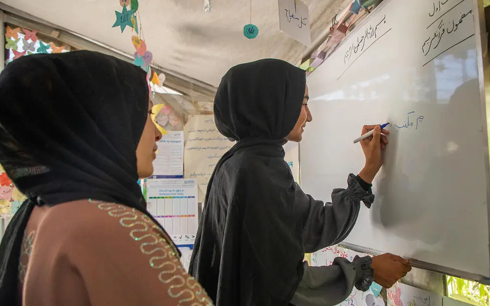 UNICEF unterstützt mit „Let Us Learn“ die Ausbildung von Lehrkräften und die Ausstattung der Lernzentren in Afghanistan. | © UNICEF/Khan Bildung in Afghanistan: Ein Mädchen und seine Lehrerin stehen vor einem Whiteboard.
