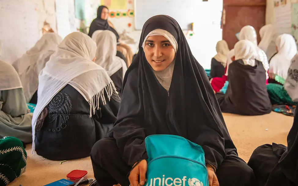 Ausreichend Lehrkräfte – insbesondere weibliche – sind entscheidend dafür, dass mehr Mädchen in Afghanistan lernen können. | © UNICEF/Khan Bildung in Afghanistan: Ein Mädchen mit Schulrucksack sitzt in ihrer Klasse auf dem Boden.