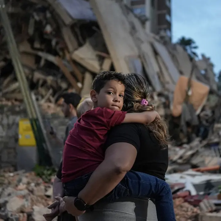 Erdbeben haben verheerende Folgen für Menschen in Venezuela verursacht. | © UNICEF/QUINTERO/AFP Erdbeben Venezuela spenden: Eine Mutter mit ihrem Kind inmitten von Trümmern. Kinder brauchen dringend Hilfe.