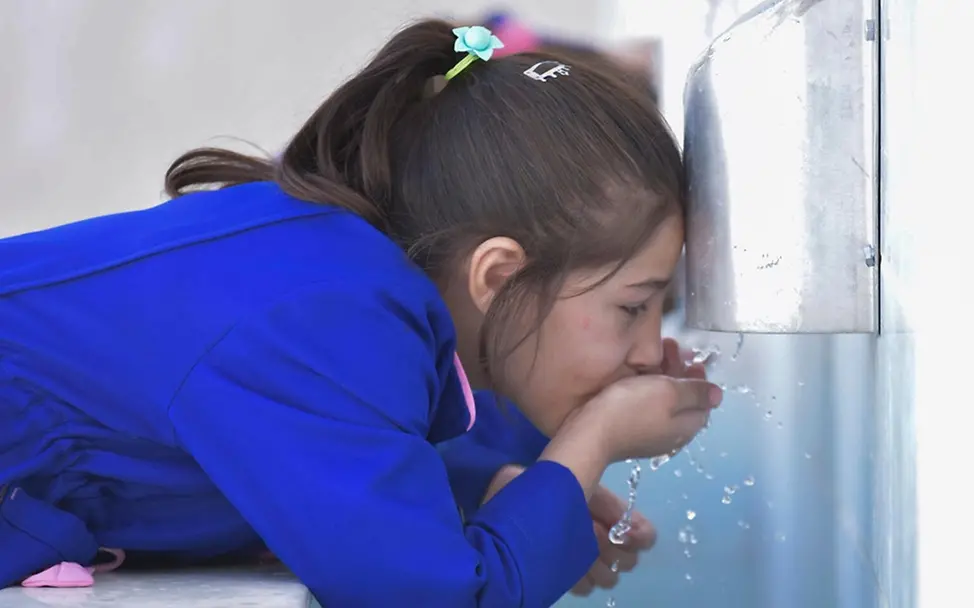 Hitze Kleinkind: Lama (10) trinkt Wasser in ihrer Schule. 