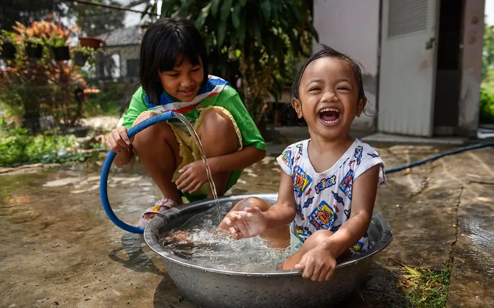 Hitze Kleinkind: Die Geschwister Khemajira Somnaijai (Nam) und Sirinda Somnaijai (Fon) spielen glücklich mit Wasser.