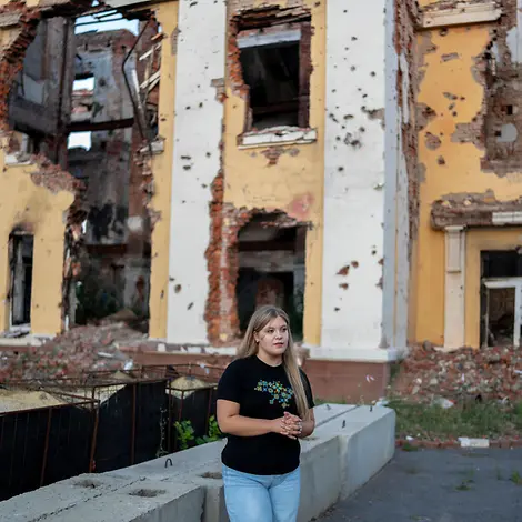 Kinder in bewaffneten Konflikten schützen: Eine Jugendliche steht vor einem zerstörten Haus in der Ukraine. 