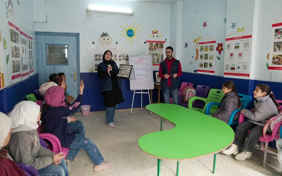 Kinderfreundliche Zentren bieten Kinder Schutz und Sicherheit | UNICEF/Shahan Syrien: Kinder sitzen um einen Schreibtisch in einem kinderfreundlichen Zentrum