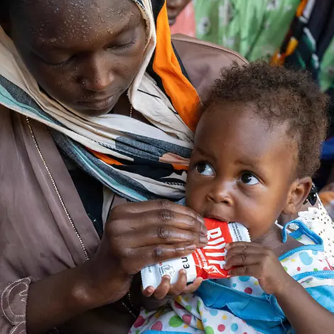 Erdnusspaste ist das wichtigste Mittel im Kampf gegen Mangelernährung bei Kindern. |© UNICEF/Dejongh Erdnusspaste Herstellung: Ein Kleinkind wird von seiner Mutter mit Erdnusspaste gefüttert.