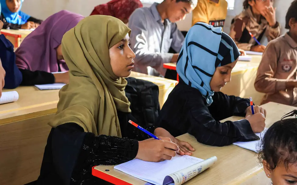 Vor allem Mädchen dürfen in vielen Ländern nicht genug lernen, sondern müssen schon früh im Haushalt arbeiten. | © UNICEF/Shareef Bildung einfach erklärt: Ein Mädchen sitzt mit Schreibblock und Stift im Klassenzimmer.
