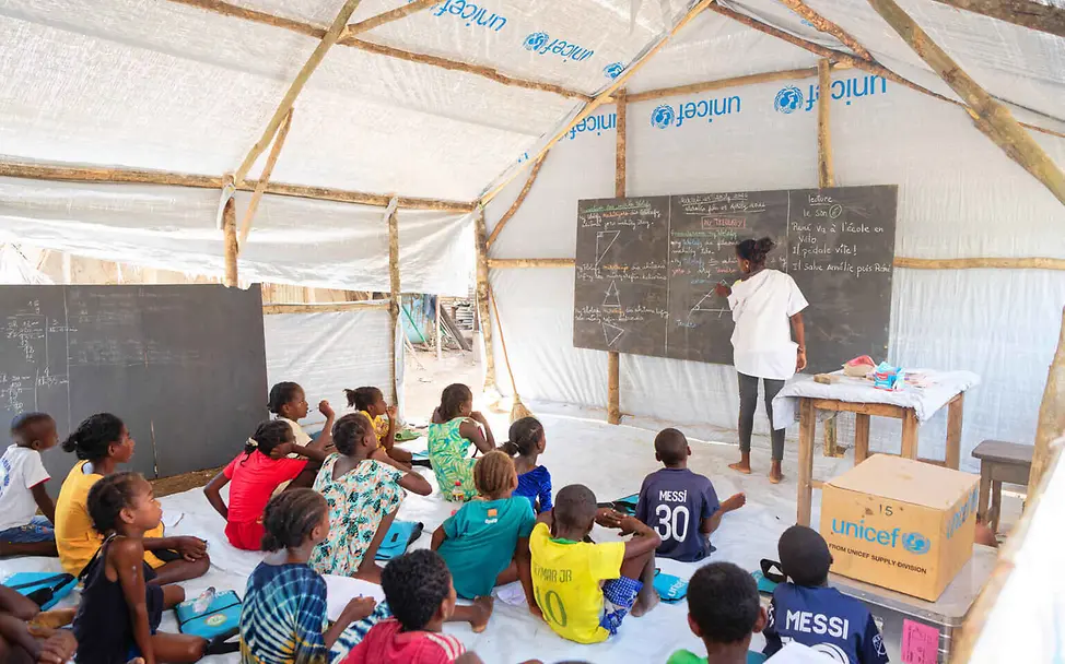 Wenn Schulen durch Konflikte oder Naturkatastrophen zerstört werden, hilft UNICEF mit provisorischen Schulräumen | © UNICEF/Ramasomanana Bildung einfach erklärt: Eine Lehrerin unterrichtet Kinder in einer provisorischen Zeltschule.