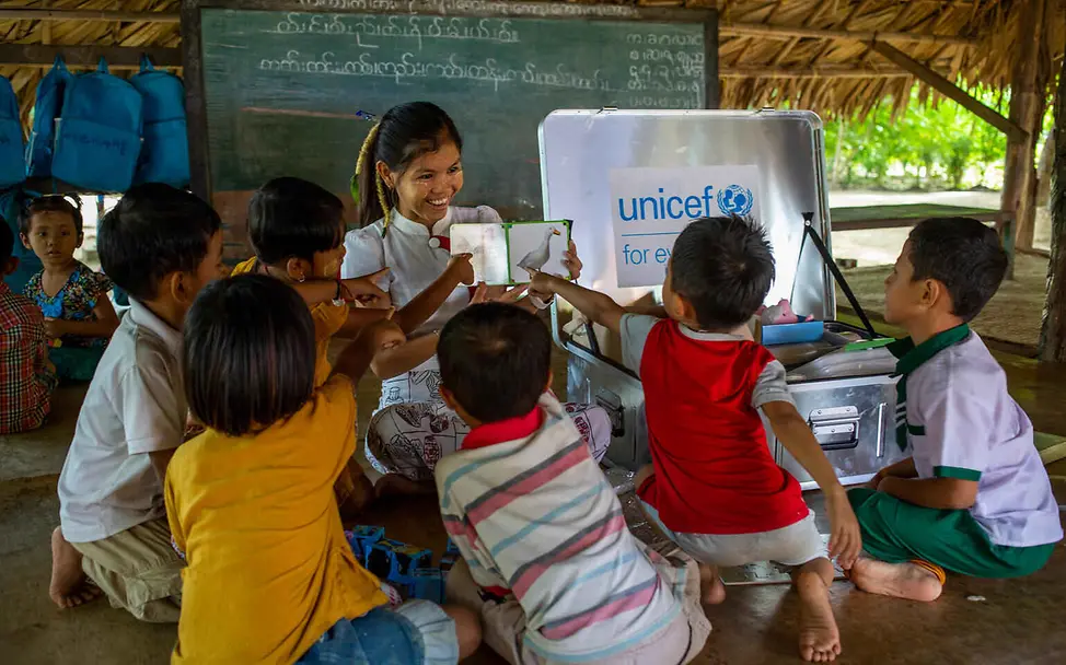 Frühkindliche Förderung hilft, Kindern den Zugang zu Bildung zu erleichtern. | © UNICEF/Htet Bildung einfach erklärt: Eine Erzieherin zeigt kleinen Kindern ein Bilderbuch.