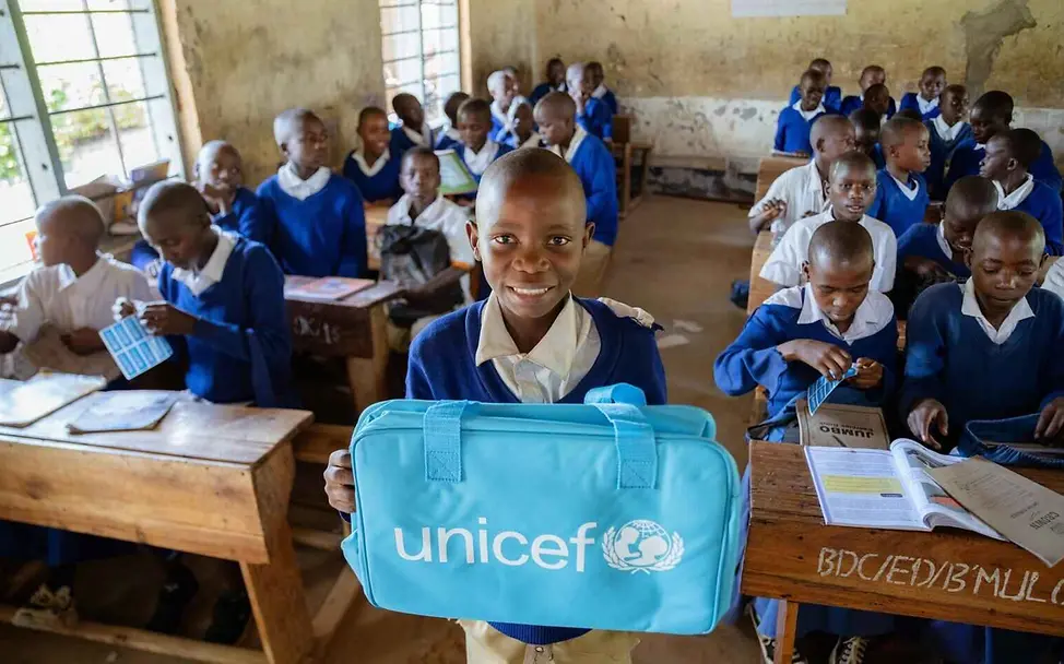 UNICEF unterstützt Schulen in vielen Ländern mit Schulrucksäcken und Lernmaterialien | © UNICEF/Kulaya Bildung einfach erklärt: Ein Schuljunge zeigt seine neue Schultasche in die Kamera