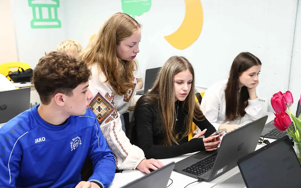 In Konfliktgebieten können Kinder aufgrund von Angriffen oft nicht regelmäßig zur Schule gehen | © UNICEF/Klochko Bildung einfach erklärt: Eine Lehrerin und Schüler arbeiten an Laptops.