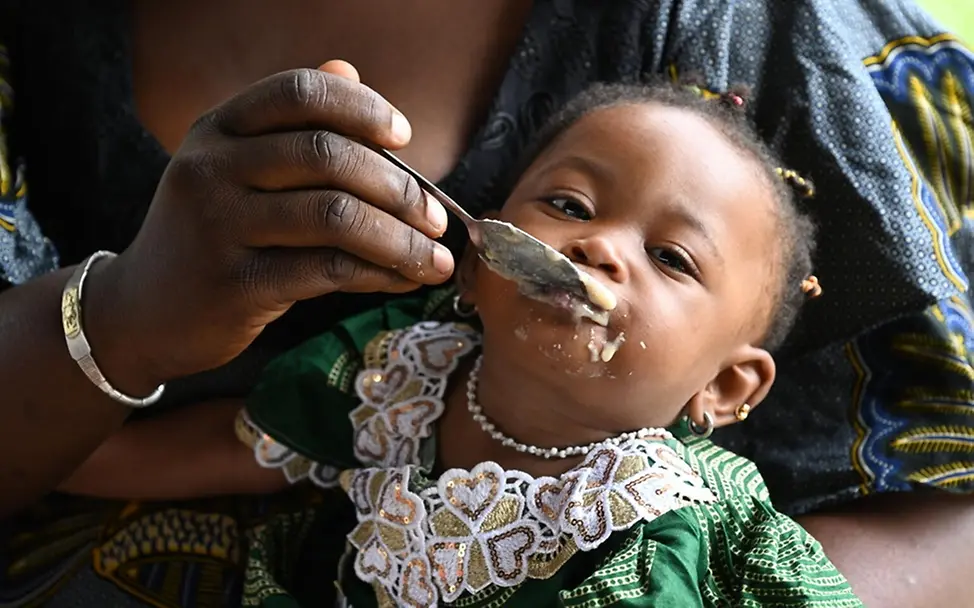 In der Elfenbeinküste erhält ein Kind Essen von seiner Mutter. | © UNICEF/Dejongh In der Elfenbeinküste erhält ein Kind Essen von seiner Mutter.