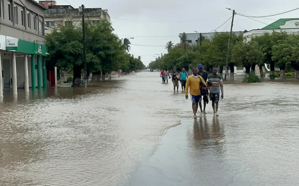Folgen von Hochwasser: Menschen laufen eine überflutete Straße entlang.