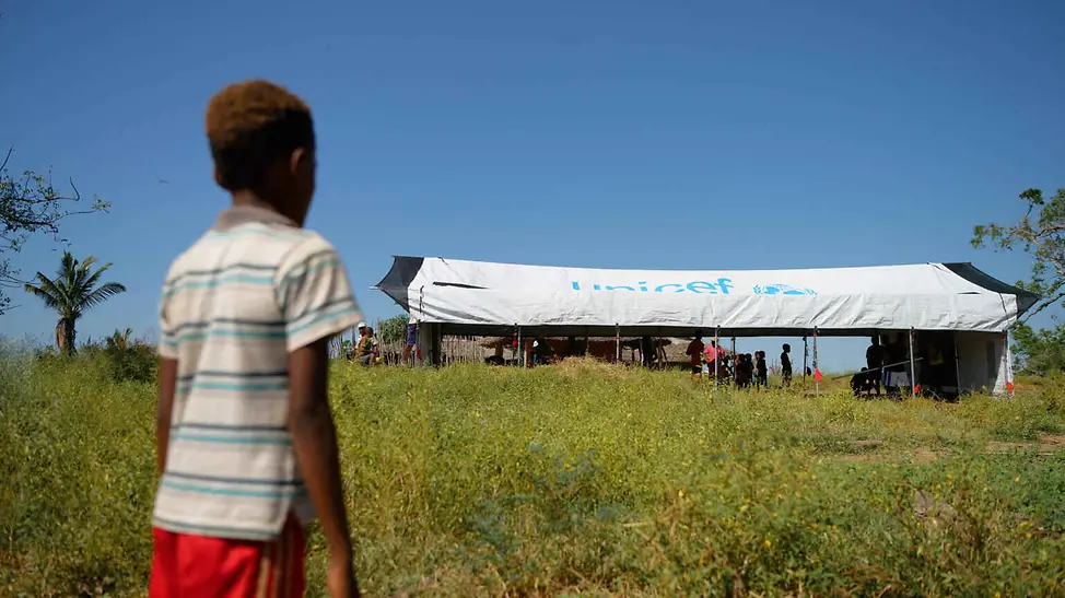 Folgen von Hochwasser: Ein Junge schaut beim Aufbau eines UNICEF-Schulzelts zu.