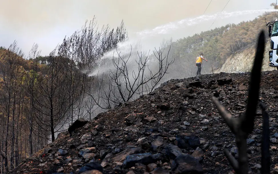 Ausgedehnte Flächenbrände zerstören nicht nur Natur und Häuser, sie verursachen auch massive Luftverschmutzung. | © UNICEF/Michalatos Waldbrand Folgen: Ein Mann beim Löschen von Bänden auf einem Hügel.