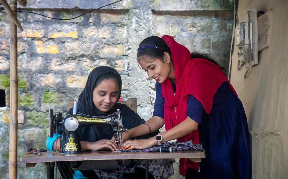Mit Let Us Learn erwerben Jugendliche praktische Fähigkeiten, wodurch sich ihnen neue Berufswege eröffnen, die Chancen auf eine bessere Zukunft bieten. | © UNICEF/Satu Bildung in Bangladesch: ein Mädchen sitzt an einer Nähmaschine und näht unter Anleitung ihrer Lehrerin.
