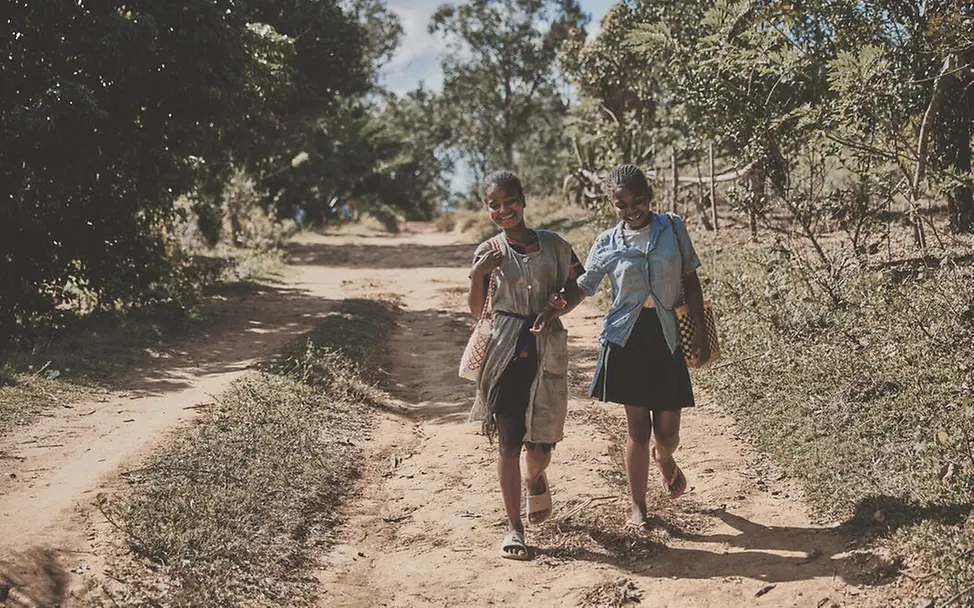 UNICEF setzt sich mit Let Us Learn dafür ein, dass Mädchen in die Schule zurückkehren und ihren Abschluss machen. | © UNICEF/Andriantsoarana Bildung in Madagaskar: Zwei Mädchen laufen einen Weg entlang zur Schule.