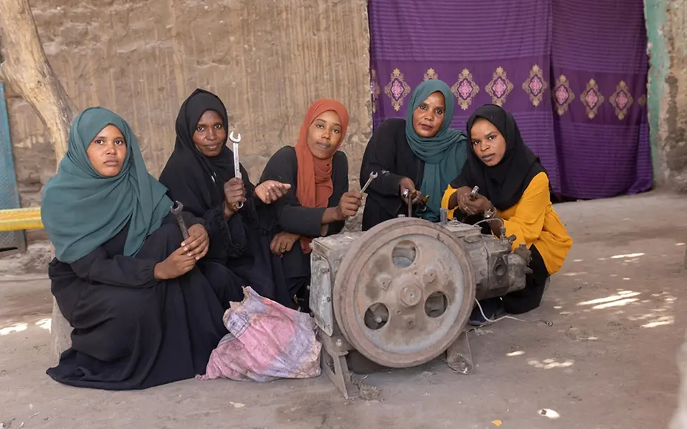Umn (16) und ihre Kolleginnen Amna, Sadiqan, Hawa und Manal vor einem Generator, den sie gemeinsam reparieren.