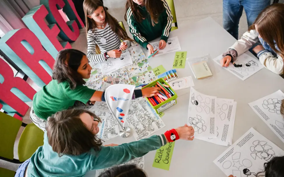 Kinder nehmen am Weltkindertag-Workshop teil und malen Bilder aus.