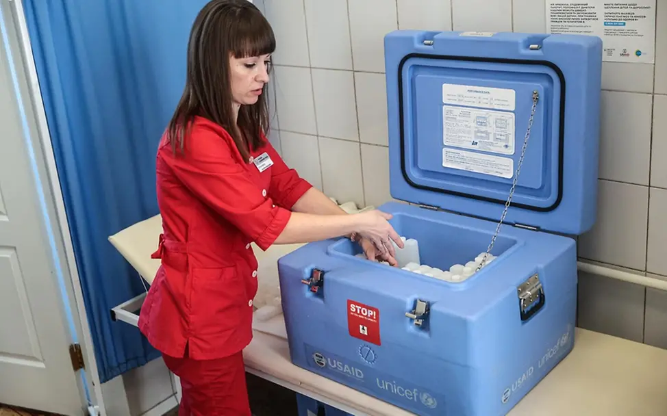 UNICEF hilft, damit möglichst viele Kinder gegen Polio geimpft werden können. | © UNICEF/ Klochko Was ist Polio: Eine Klinikmitarbeiterin verstaut Impfstoffe in einer blauen Kühltruhe.